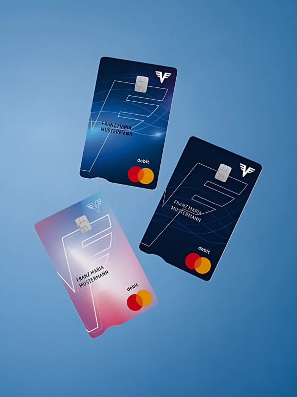 Drei Volksbank-Bankkarten auf blauem Hintergrund.